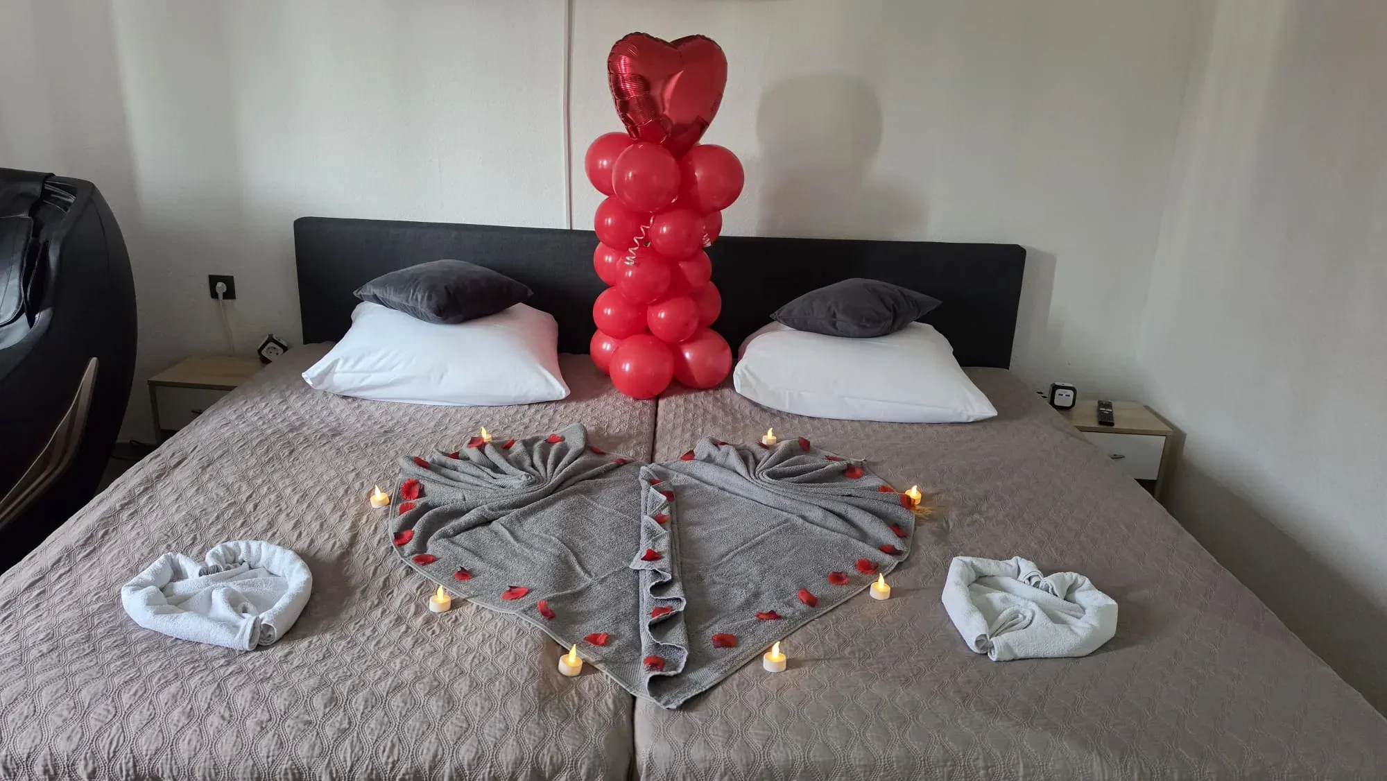 Festlich dekoriertes Doppelbett mit Handtuchherz und rotem Herzballon
