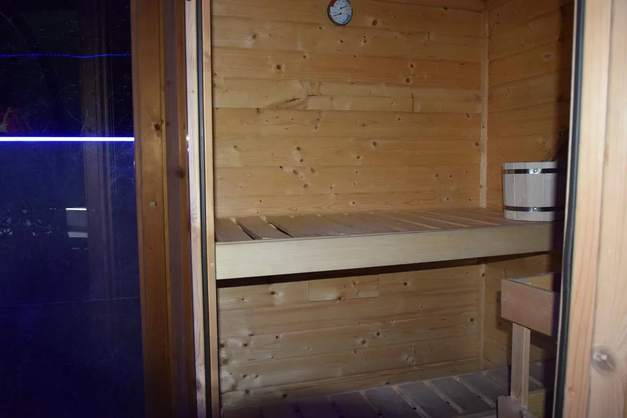 Innenansicht der privaten Sauna mit Holzbänken und Aufgusskübel
