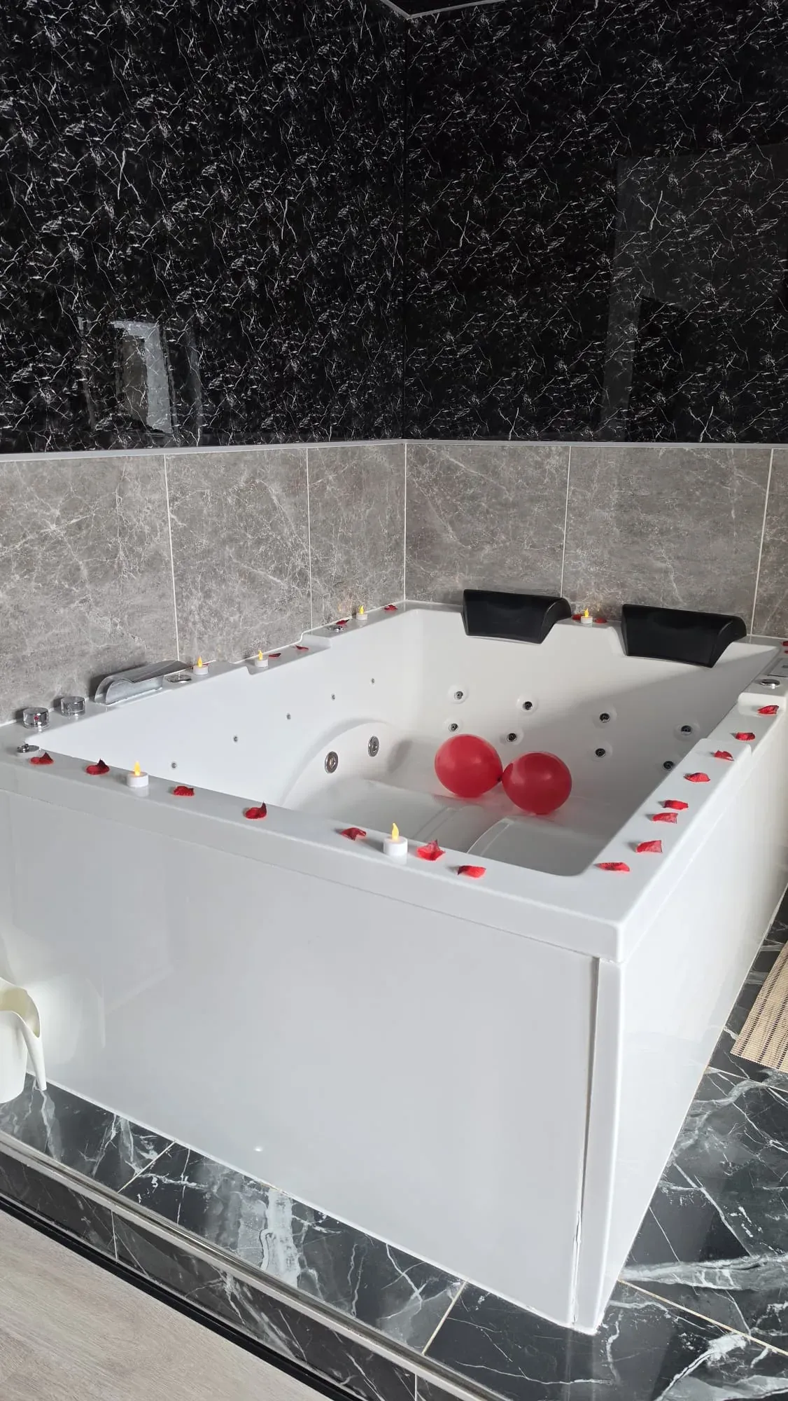 Whirlpool mit Rosenblättern, Kerzen und roten Herzballons