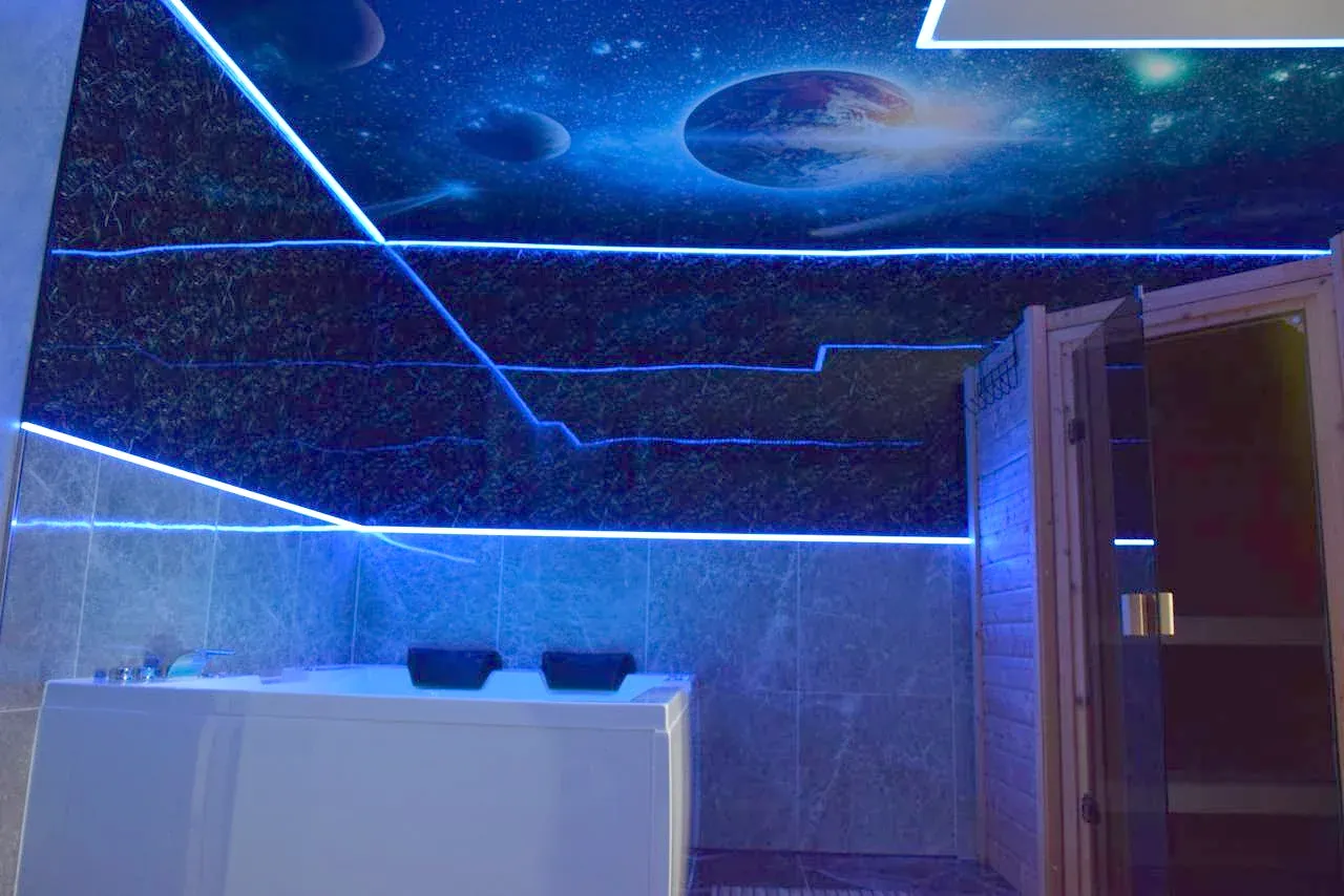 Private Sauna mit Glastür direkt neben dem Whirlpool, darüber die Sternenhimmel-Decke mit Planetenmotiv